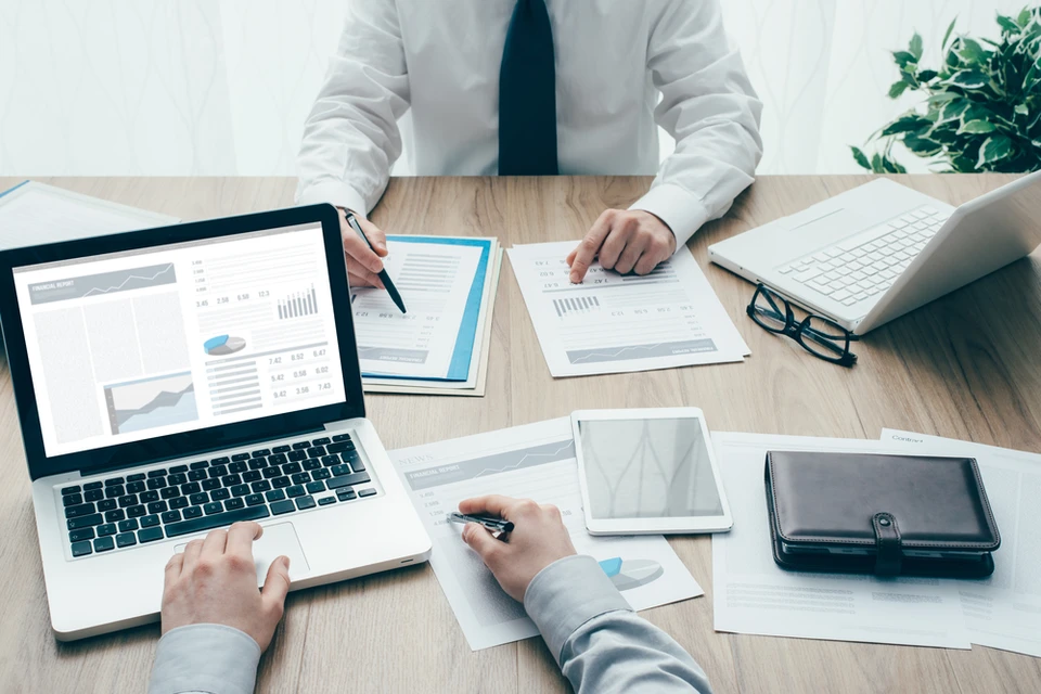 Réunion d'affaires dans bureau moderne avec deux hommes en costume analysant des rapports financiers