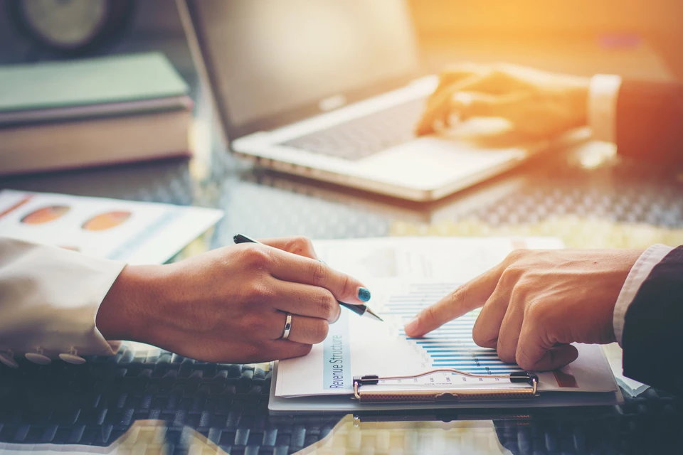 Scène de travail en bureau avec personne analysant des documents financiers sur une table
