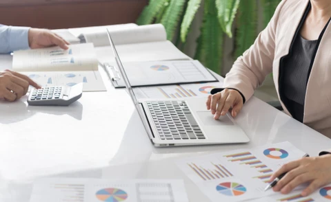 Divers collègues d'affaires discutant des documents utilisés pour accompagner la réunion mensuelle de l'entreprise, des gens d'affaires multidisciplinaires discutant du rapport de vente annuel de l'entreprise aux participants